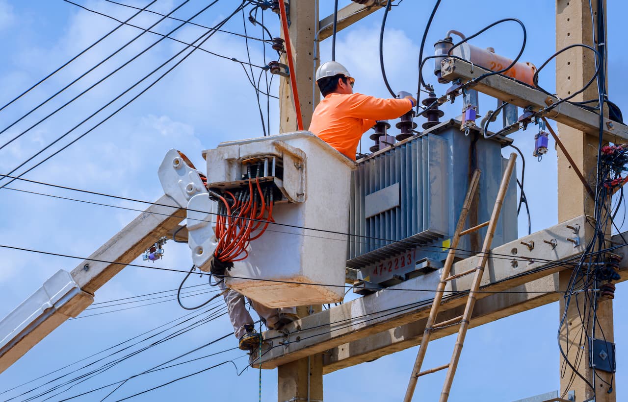 Técnico trabajando en una subestación eléctrica desde una grúa, con equipo de protección completo disponible en Ferreterías Guevara