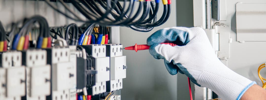 Trabajador usando destornillador en un panel eléctrico, equipo de Ferreterías Guevara