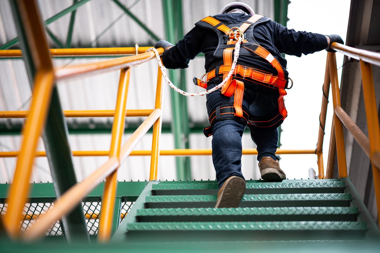 Operario subiendo escaleras con equipo de protección para alturas Ferreterías Guevara