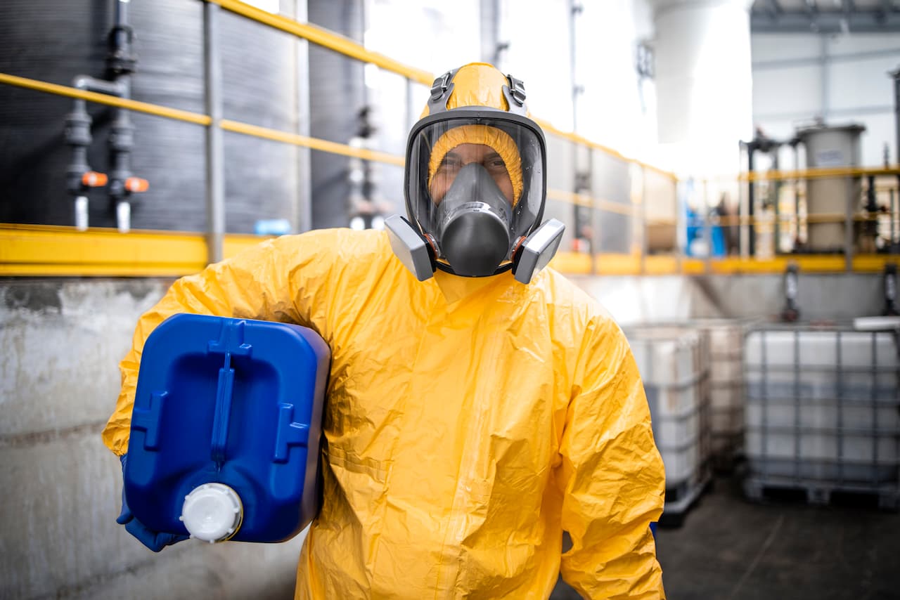 Profesional equipado con traje de protección y máscara respiratoria en un ambiente industrial, utilizando equipos de Ferreterías Guevara