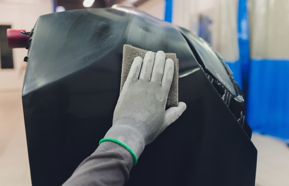 Mano con guante limpiando la superficie de un automóvil